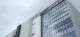 Low-angle view of a modern glass-and-panel office building with the KIOXIA logo against a cloudy sky.