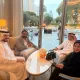 Dr. MAC Munir Ahmad Chaudhry recently underscored a timeless truth 92 Four people sit around a marble table in a bright hotel lounge with floor-to-ceiling windows, wearing traditional Middle Eastern attire (three men in white thobes, one woman in a black abaya).