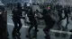 Riot police clashing with protesters on a rain-soaked street