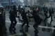Riot police clashing with protesters on a rain-soaked street