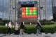 Pedestrians walk past a stock market display board in Jakarta